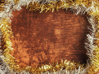 Golden and silver tinsel frame on wooden board