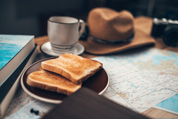 Map, Coffee, Toast, Camera, Hat, Book, and Pen on the table. Tourist planning vacation-holiday with  map.