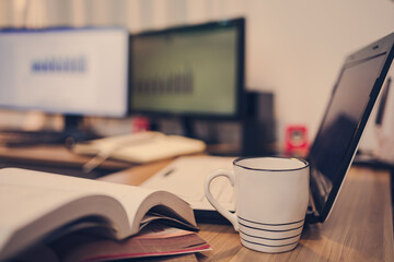 Cup of coffee, Book, Document file and laptop on workplace at home night. Work at home and  Education at home concept.
