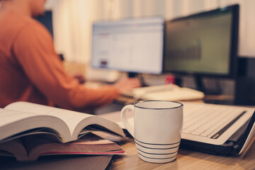 Cup of coffee, Book, Document file and laptop on workplace at home night. Work at home and  Education at home concept.