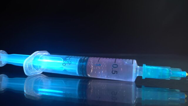Syringe in Macro. Glass surface with reflection. Novel Coronavirus (2019-nCoV) Corona virus vaccine vial dose flu shot drug needle syringe medical concept vaccination hypodermic injection treatment