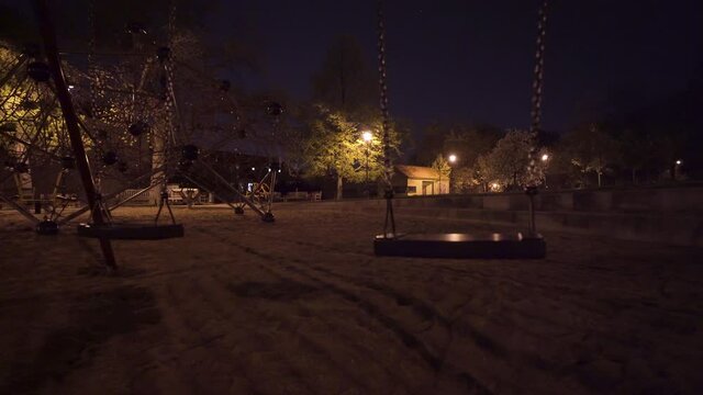 Empty swing set seat moving,children playground at night,Prague,Czechia,lockdown.