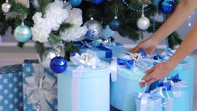 hands of a girl steal a gift under a Christmas tree with a blue decor
