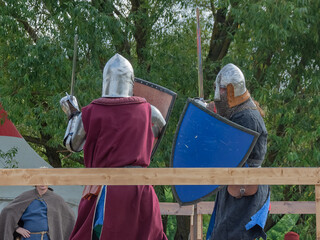 Two foot warriors in heavy medieval armor fight in the arena. Armed with swords. They are protected...