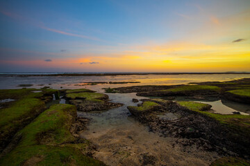 Seascape. Beach with rocks and stones. Low tide. Sunset time. Slow shutter speed. Soft focus. Melasti beach, Bali, Indonesia