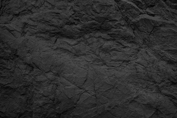 Black stone background. Dark gray rock texture. Rough stone surface with cracks.
