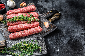 Fresh raw beef meat kebabs sausages on a cutting board. Black background. Top view. Copy space