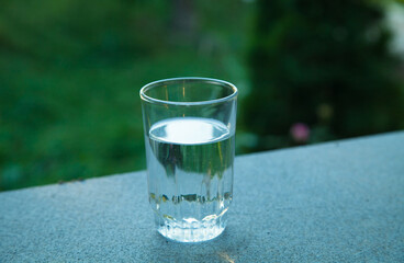 Drinking water glass against the background of green nature.