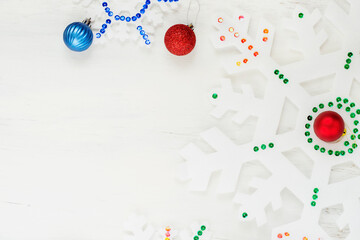 Snowflakes and Christmas decorations on a white wooden background.