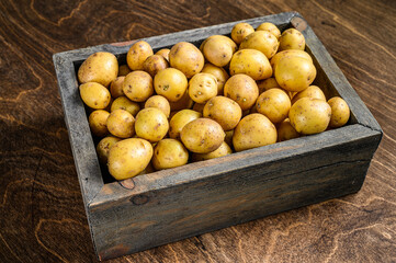 Young baby Potatoes in a wooden box. Wooden background. Top view