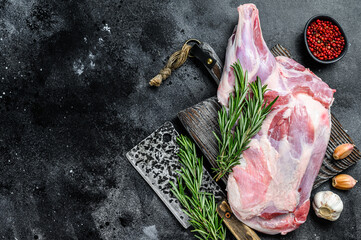 Raw lamb shoulder meat ready for baking with garlic, rosemary. Black background. Top view. Copy...