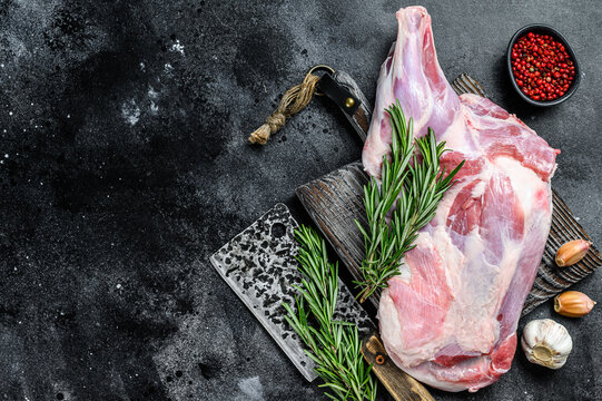 Raw lamb shoulder meat ready for baking with garlic, rosemary. Black background. Top view. Copy space