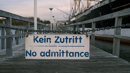 a white sign hanging on a chain says: no admittance