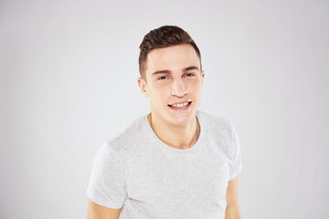 Man in a white t-shirt emotions gestures with hands close-up cropped view light background