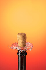 cork flies out of a bottle of champagne under pressure with stream and splash on colored background