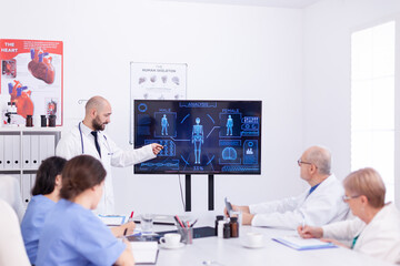 Obraz premium Medical practioner holding presentation about human system in front of coworkers wearing lab coat.