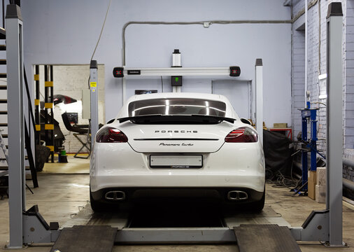 Moscow. November 2018. White Porsche Panamera At The Wheel Alignment Stand Of The Service Center. Sports Porsche, Executive Class Sedan In The Tuning And Repair Center.