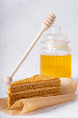 Fototapeta na wymiar selective focus. honey cake with delicate cream. on a light background with craft paper. in the background is a jar of light honey