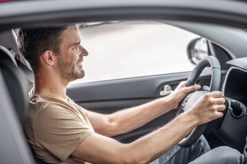 Young male sitting in car, holding steering wheel