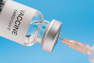Vaccine vial with syringe isolated over blue background. Medical concept shows a medical vial and...