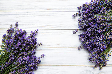 Fototapeta premium Fresh flowers of lavender bouquet, top view on white wooden background