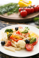 Plate with tasty pasta primavera on table, closeup