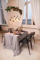Side view of festive Christmas table setting with empty wine glasses and black plate