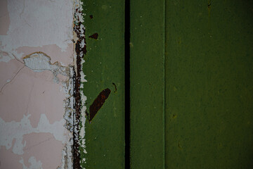 Metal sheet, garage detail, wall screwed in with bolts, nuts, screws, traces of green, emerald paint with elements of rust and metal corrosion, cracks, barn lock and grate