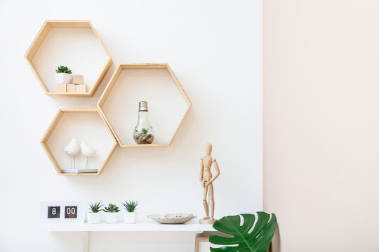 Shelves with wooden mannequin and houseplants on wall in room