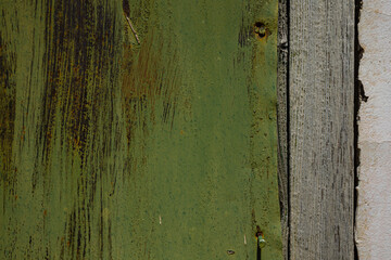 Metal sheet, garage detail, wall screwed in with bolts, nuts, screws, traces of green, emerald paint with elements of rust and metal corrosion, cracks, barn lock and grate