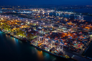 Container ship loading and unloading in deep sea port, Aerial view at night