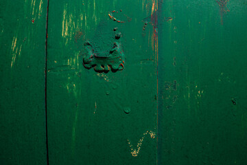 Metal sheet, garage detail, wall screwed in with bolts, nuts, screws, traces of green, emerald paint with elements of rust and metal corrosion, cracks, barn lock and grate