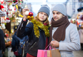 Smiling girl with boy choosing decorations at Christmas market