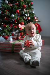 A baby toddler near a Christmas tree