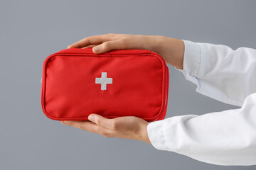 Doctor's hands with first aid kit on grey background