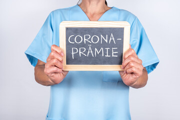 Krankenschwester oder Altenpflegerin mit einer Tafel auf der CORONA PRÄMIE steht