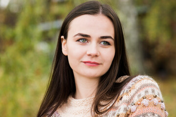 Naklejka premium Portrait of a dark-haired green-eyed woman on the background of nature 