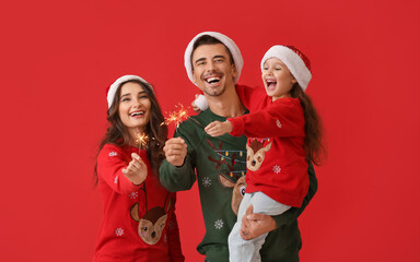 Happy family with Christmas sparklers on color background