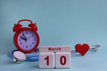 10st March. White wooden calendar blocks with date, clock and stethoscope on a blue pastel...