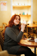 Caucasian beautiful plus size lady overweight woman eating a chocolate cake in a cafe. Difficult choice concept, diet or delicacy. Brunette woman with long hair in a cafe