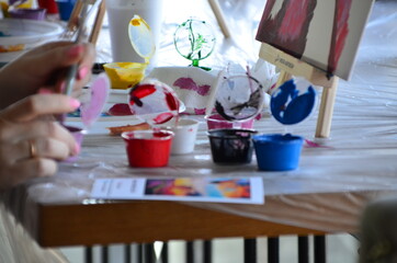 Pretty smiling young woman drawing a picture with paint. Front view on drawing girl with palette. Smiling young woman draw a picture at studio. drawing in a cafe. master drawing class. modern hobby