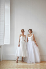 Fototapeta premium Two Beautiful slender woman in white wedding dress, new collection of dresses for the bride. Noise, out of focus