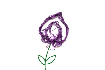 Purple flower made of thread on white background. Stem and leaves painted. Copy space.
