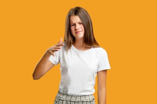 Confused Child. Dont Know. Bad Idea. Hard Choice. Clueless Uncertain Teen Girl Showing So-so Gesture Isolated On Orange Copy Space Background.