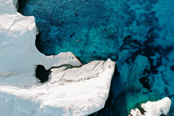 Aerial drone photographs of Sarakiniko Beach moonscapes in Milos Island, Greece surrounded by crystal clear turquoise waters and waves of the Aegan Sea