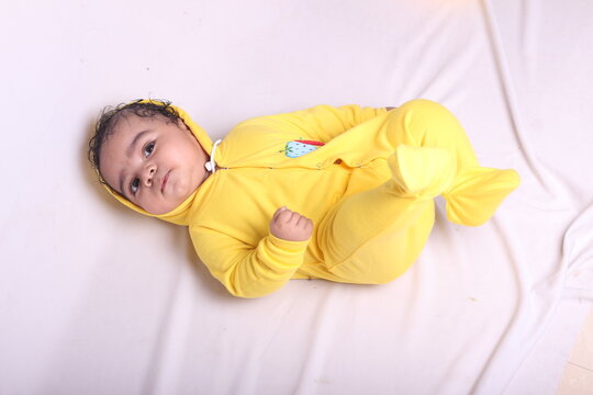 2 Months Old Baby In Yellow Jumpsuit On A White Background