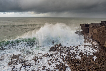 Powerful waves hit the rough stone coast line creating huge splashes of water. Low dark storm clouds, West of Ireland. Nobody.