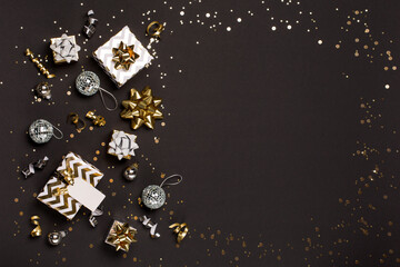 Gold and silver decorations, mirror disco balls, gifts on dark black background. Christmas, winter, new year concept.