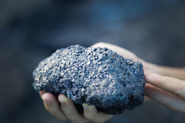 Hand of a woman holding a volcanic stone on the lava flows of the Piton de la Fournaise volcano on Reunion Island