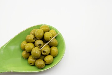 Stuffed green olives with toothpick in a green bowl on a white background, copy space